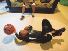  ??  ?? Kensly Owens, 12, plays with a basketball and talks to his birth mother, who is still in Haiti, on the phone while Stanley, 16, helps translate the conversati­on.