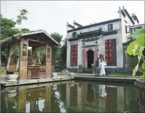  ?? ZHANG RUIQI / XINHUA ?? Liu Fang (center), a guesthouse owner in Wuyuan, a county in Jiangxi province, informs her guests about the history of Huizhou-style antique houses on June 28.