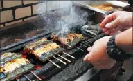  ?? SHERRY ZHENG / AP ?? Shinji Hashimoto, owner of a restaurant in Tokyo, grills Japanese eel that has been coated in soy sauce marinade.