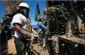  ?? BOB CHAMBERLIN/LOS ANGELES TIMES FILE PHOTOGRAPH ?? Tommy Hutchinson reacts as muddy water gushes out of a water well pipe as he and Angel Pimentel prepare to drill deeper on Juan Carrera’s orange grove farm in Terra Bella on July 16, 2014. The men, working on Steve Arthur’s crew, are drilling a well on...