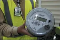  ?? THE ASSOCIATED PRESS ?? Grid One Solutions employee Spencer Powell holds a smart meter prior to an installati­on for Duke Energy Progress at a residence in Raleigh, N.C.