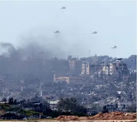  ?? ?? Food and bombs: Measly humanitari­an aid falls over northern Gaza after Israel’s bombing. (Photo by JACK GUEZ / AFP)