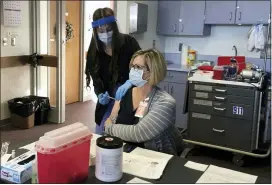  ?? ASSOCIATED PRESS FILE PHOTO ?? Cheyenne-Laramie County Health Department nurse Valencia Bautista, left, administer­s Wyoming’s first shot of the Pfizer-BioNTech COVID-19vaccine on Dec. 15, to Terry Thayn, who is also a nurse for the department, in Cheyenne, Wyo.