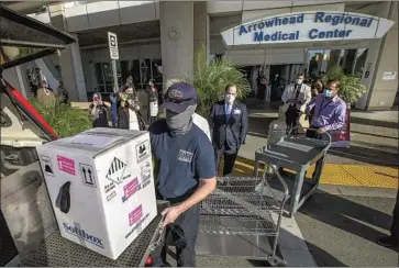  ?? I rfan Khan Los Angeles Times ?? A SAN BERNARDINO COUNTY f iref ighter unloads a box carrying the f irst batch of the Pfizer- BioNTech vaccine against COVID- 19 to be received at Arrowhead Regional Medical Center in Colton on Wednesday.