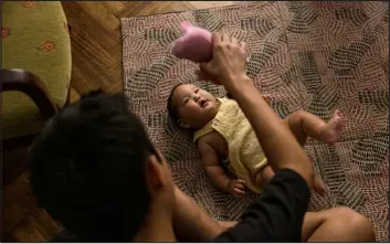  ?? PHOTOS BY SARAH PABST — THE NEW YORK TIMES ?? Aisen Sergeev plays with his 4- month- old son, Duolan, last month at their apartment in the capital of Argentina. Duolan was born in Argentina.