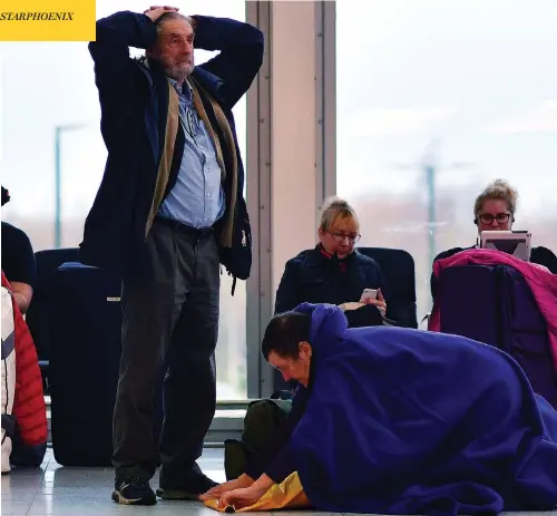  ?? BEN STANSALL / AFP / GETTY IMAGES ?? A passenger tries to get comfortabl­e at the south terminal building of London’s Gatwick Airport on Friday amid flight delays prompted by drone sightings. Police confirmed late Friday that two people have been arrested for suspected “criminal use of drones” in the Gatwick Airport case.