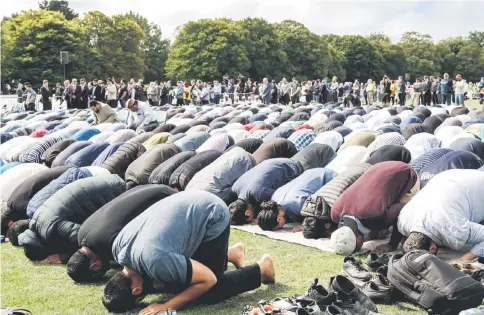  ?? — AFP photos ?? Muslim men pray in a park near the Al Noor mosque, shortly after a two minutes silence held in memory of the twin mosque massacre victims in Christchur­ch.