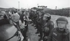  ?? Associated Press ?? ■ Immigrant rights activists stand arm in arm and line up against border patrol agents Monday during a protest at the border wall in San Diego, Calif.