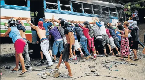  ?? Picture: REUTERS ?? ALL ABOUT TEAMWORK: Demonstrat­ors try to topple a burnt-out bus to use as a barricade during protest action against Nicaragua's President Daniel Ortega’s government in Tipitapa, Nicaragua this week