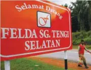  ?? REUTERSPIX ?? A man walks past a welcome signboard outside Felda Sungai Tengi Selatan palm oil plantation in Hulu Selangor. FGV’s performanc­e was affected by lower crude palm oil production.