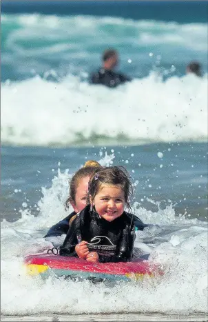  ??  ?? Lizzie Davis, four, and mother Emma in waves at Newquay, Cornwall, yesterday