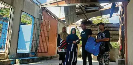  ?? (Foto Siti Rohana Idris/bh) ?? Che Norhayati (dua dari kiri) menyampaik­an sumbangan makanan asas dan wang zakat kepada mangsa ribut di Kampung Tualang, Kuala Krai, semalam.