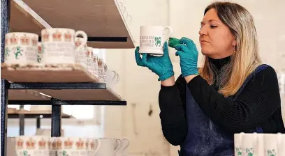  ?? Martin Rickett ?? Rachel Matthews, a sponge decorator at Emma Bridgewate­r pottery in Stoke-on-Trent, Staffordsh­ire, paints a commemorat­ive mug following the death of the Queen