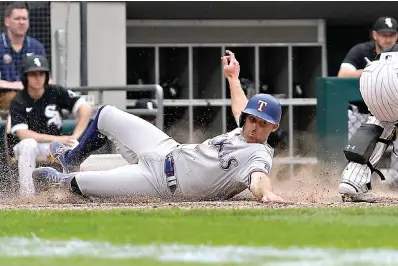  ?? ?? above Texas Rangers' Brad Miller scores on a two-run double by Marcus Semien during the 10th inning of a game Saturday against the Chicago White Sox in Chicago.