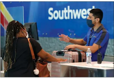  ?? (AP) ?? A Southwest Airlines employee helps a passenger last month at the ticket counter at Love Field in Dallas.