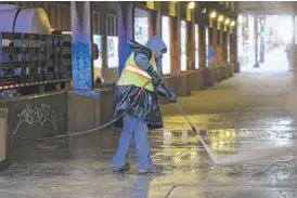  ?? ?? A worker with the city’s Department of Streets and Sanitation cleans the sidewalk under a viaduct in the West Loop where a homeless encampment has grown in recent months.