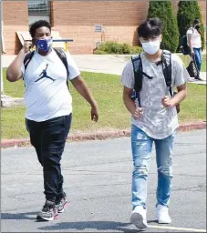  ?? Westside Eagle Observer/MIKE ECKELS ?? Konner Hunt (left) and Enrique Rubi walk between the main high school building and Peterson Gym on Aug. 24 during the opening day of the 2020-21 school year. Students are required to wear masks due to state covid-19 mandates.