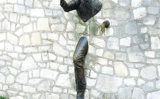  ??  ?? Il monumento in Place Marcel-Aymé, nel quartiere parigino di Montmartre. La statua bronzea raffigura lo scrittore ed è basata sul suo racconto intitolato
Le passe-muraille ( Il passamura)