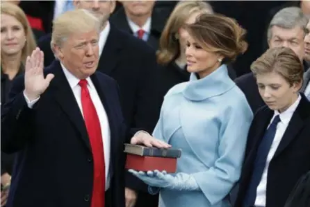  ?? FOTO'S AFP, EPA ?? Trump legt de eed af terwijl zijn vrouw Melania de bijbel vasthoudt. Ook zoon Barron is erbij.