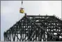  ?? TONY GUTIERREZ — THE ASSOCIATED PRESS FILE ?? Workers reach for a transport vehicle lowered to their position at the very top the roof structure currently under constructi­on atop Globe Life Field as a light rain falls in Arlington, Texas.