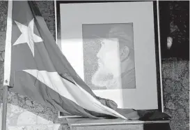  ?? Ramon Espinosa / Associated Press ?? An image of Fidel Castro and a Cuban flag are displayed in honor of the late leader inside the foreign ministry in Havana on Saturday, one day after his death.