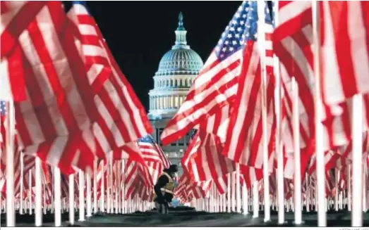  ?? JUSTIN LANE / EFE ?? Una persona pasa ayer entre las 200.000 banderas instaladas frente al Capitolio para la investidur­a hoy del demócrata Joe Biden.