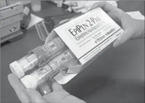  ??  ?? Una farmaceuta muestra dos autoinyecc­iones EpiPen, de epinefrina, que se usa para tratar la anafilaxia