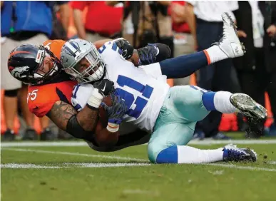 ?? Associated Press ?? n Dallas Cowboys running back Ezekiel Elliott (21) is tackled by Denver Broncos cornerback Chris Harris during the second half of an NFL football game Sunday in Denver.