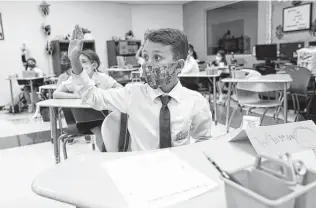 ?? Lynne Sladky / Associated Press ?? Winston Wallace, 9, raises his hand in class at iPrep Academy on the first day of school in Miami. A judge has ruled that Florida school districts may impose mask mandates.