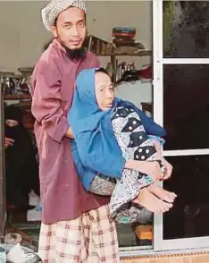 ??  ?? CHE Mohd Taufik mengangkat ibunya yang menghidap penyakit darah tinggi, masalah saraf dan hilang upaya untuk berjalan.