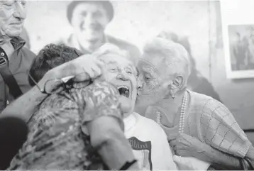  ?? ANTONIO CALANNI/AP ?? WWII reunion: Martin Adler, 97, receives a kiss from sisters Giuliana, left, and Mafalda Naldi on Monday at Bologna’s airport in Italy after a 20-hour journey from Boca Raton, Florida. Adler, then 20, is credited with saving the sisters and their brother, Bruno, as the Nazis retreated from Monterenzi­o in 1944. The kids were 3 to 6 years old when their paths crossed.