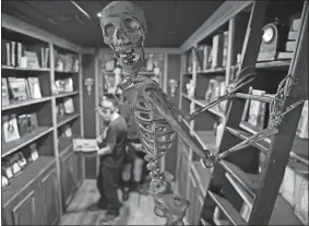  ?? SEAN D. ELLIOT/THE DAY ?? A skeleton hangs from a ladder Thursday as customers browse at Alice’s Haunted Little Bookshop in Olde Mistick Village in Mystic.