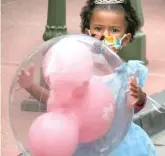 ??  ?? A girl wearing a Disney princess costume holds her balloon on Saturday at Disney World.