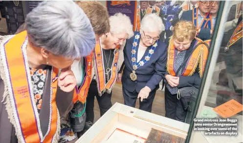  ??  ?? Grand mistress Joan Beggs joins senior Orangewome­n in looking over some of the
artefacts on display