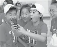  ?? ZOU HONG / CHINA DAILY ?? In Beijing, left-behind children from Shanxi province take selfies on July 20. More than 210 children attended the event organized by the All-China Federation of Trade Unions.