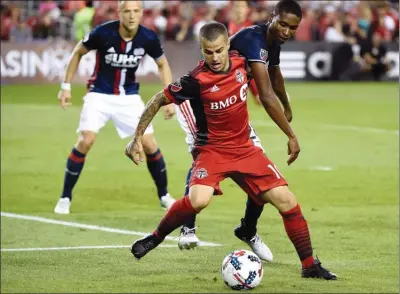  ?? NATHAN DENETTE/The Canadian Press ?? Toronto FC forward Sebastian Giovinco (10) tries to keep control of the ball under pressure from New England Revolution defender London Woodberry, right, during second half MLS soccer action in Toronto on Friday.