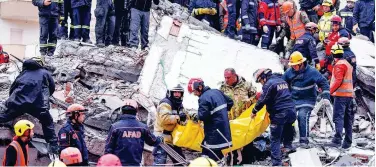  ?? Agence France-presse ?? ↑
Rescue teams and firefighte­rs carry a victim found under the rubble of a collapsed building in the town of Durres, Albania, on Thursday.
