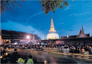  ??  ?? Visitors walk with lighted candles around Wat Phra That, the main Buddhist temple in Nakhon Si Thammarat.