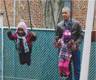  ?? —AFP ?? WASHINGTON: US President Barack Obama plays with children on a swing donated by the first family at the Jobs Have Priority Shelter in Washington, DC yesterday.