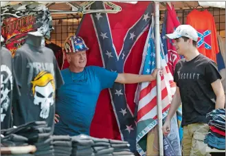  ?? JOHN BAZEMORE/AP PHOTO ?? Souvenir vendor Ed Sugg, left, talks with a customer at his facility near Talladega Superspeed­way prior to a NASCAR Cup race on Sunday in Talladega Ala.