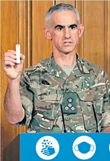  ??  ?? British Army Brigadier Joe Fossey, who is involved in the mass coronaviru­s testing pilot in Liverpool, holds up the components of a Covid-19 test as he speaks during a virtual press conference on the pandemic in London, alongside Boris Johnson, the Prime Minister