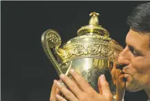  ?? NEIL HALL/POOL VIA AP ?? Novak Djokovic kisses the trophy Sunday after defeating Kevin Anderson in the men’s singles final match at the Wimbledon Tennis Championsh­ips in London.