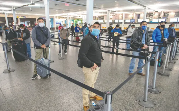  ?? Ryan
Remior
z / th
e canadian
pr
ess ?? Migrant workers from Mexico maintain social distancing as they wait to be transporte­d to Quebec farms after arriving Tuesday at Trudeau Airport.