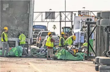  ?? MICHAEL SCHENNUM/THE REPUBLIC ?? Workers clean up after a semitruck overturned Thursday on Interstate 10, killing the driver.