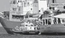  ??  ?? During a migrant transfer on Tuesday, an Italian Coast Guard boat, foreground, pulls up alongside a ship from SOS Mediterran­ee, a migrant advocacy group from Europe.