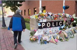  ?? The Canadian Press ?? A resident views the makeshift tribute outside the police station in Fredericto­n on Saturday. Two city police officers were among four people who died in a shooting in a residentia­l area on the city’s north side.