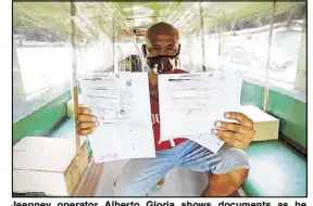  ?? BOY SANTOS ?? Jeepney operator Alberto Gloria shows documents as he prepares a unit to conform to safety standards at a depot in Quezon City. A total of 6,002 traditiona­l jeepneys with approved routes have been allowed to resume operations today.