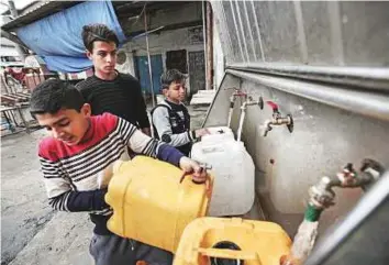  ?? AFP ?? Palestinia­n children filling jerrycans with drinking water from public taps at the Rafah refugee camp in the southern Gaza Strip.