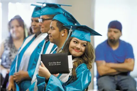  ?? PHOTOS BY LUIS SÁNCHEZ SATURNO/THE NEW MEXICAN ?? Ashley Diaz of Capital High School shows her diploma to her family Wednesday during the summer graduation ceremony for 21 students at Santa Fe Public Schools’ Educationa­l Services Center.