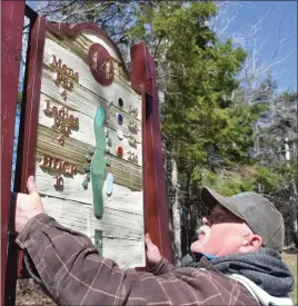  ?? KEVIN ADSHADE/THE NEWS ?? David Crouse, an employee at Abercrombi­e Golf & Country Club, gets ready to hang the sign on the 14th tee.